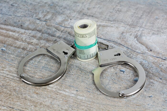 How to get your grocery budget under control in 2024  - image is a roll of bills with a pair of handcuffs